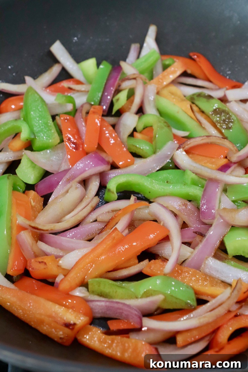 cooked sliced bell peppers and onions in skillet