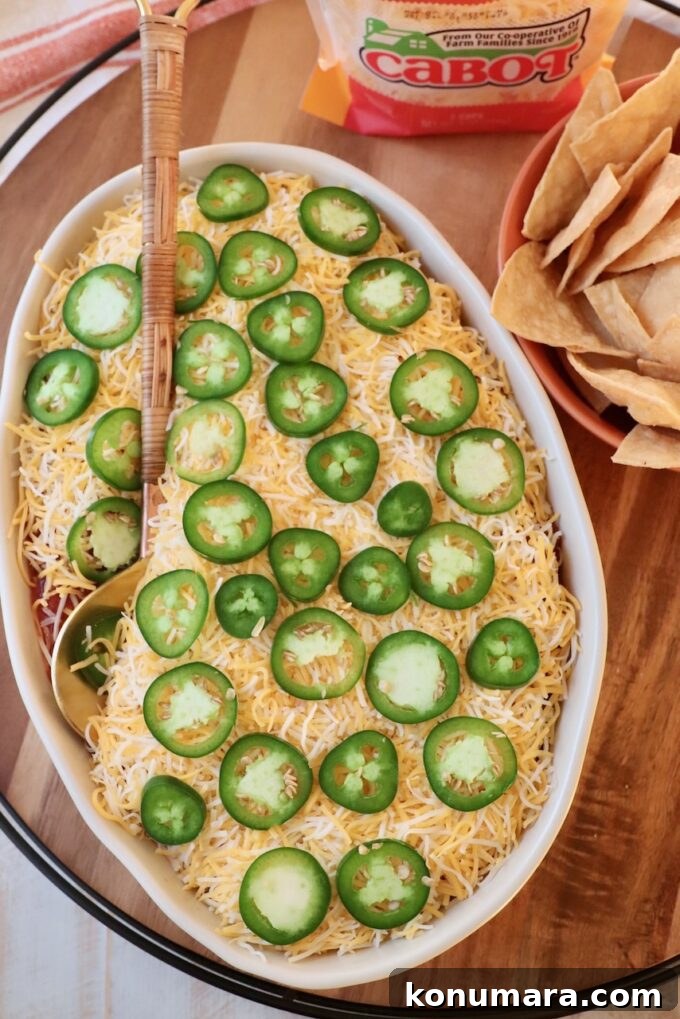 seven layer dip in casserole dish with serving spoon