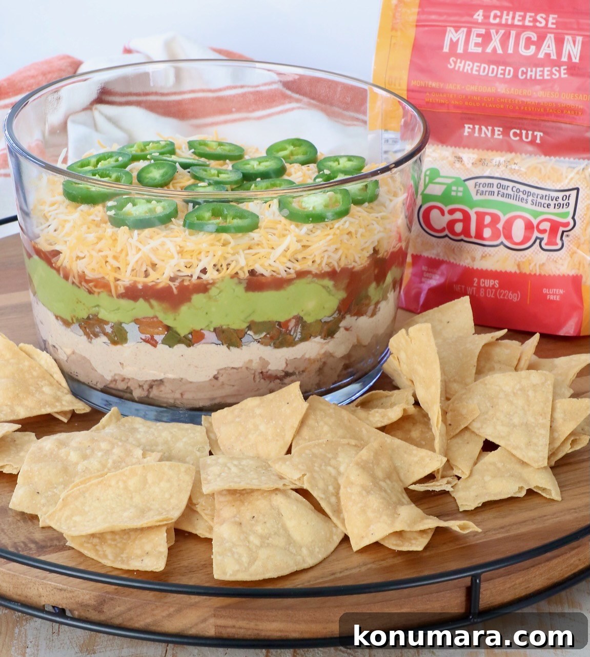 7 layer dip in glass trifle surrounded by tortilla chips on serving tray