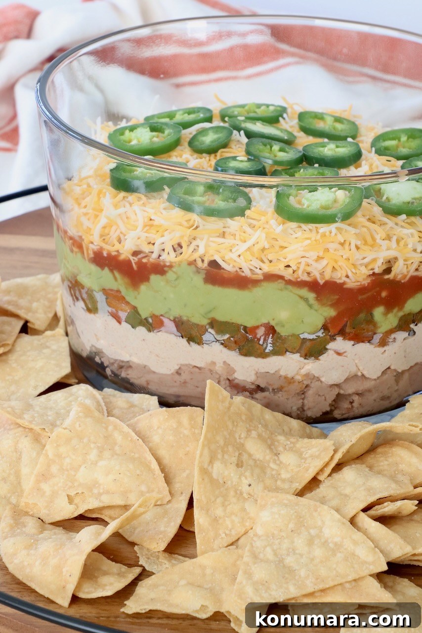 seven layer dip in glass trifle on serving tray with tortilla chips