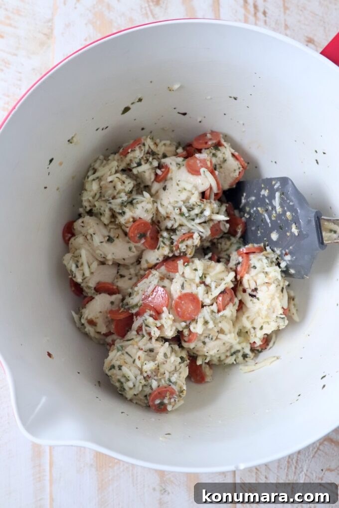 biscuit dough mixed with pepperonis, cheese and italian seasoning in bowl