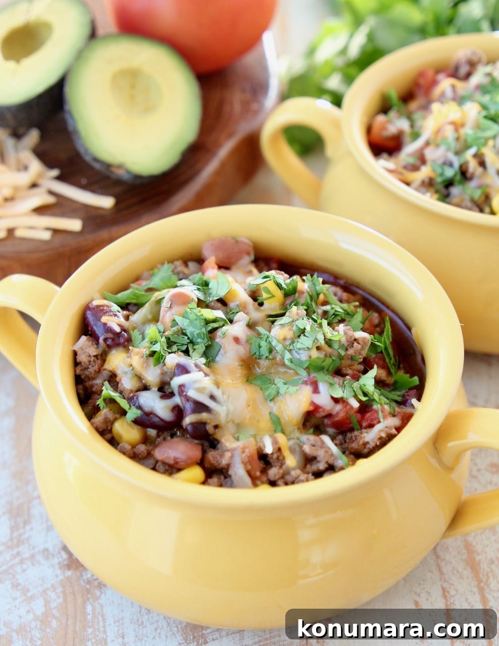 Slow Cooker Taco Soup with Ground Beef and Beans 2 Taco soup in a yellow crock with cheddar cheese and fresh cilantro