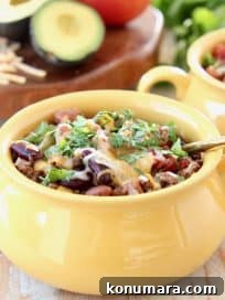Slow Cooker Taco Soup with Ground Beef and Beans 12 Crockpot Taco Soup in yellow crock with gold spoon, topped with cheddar cheese and fresh cilantro