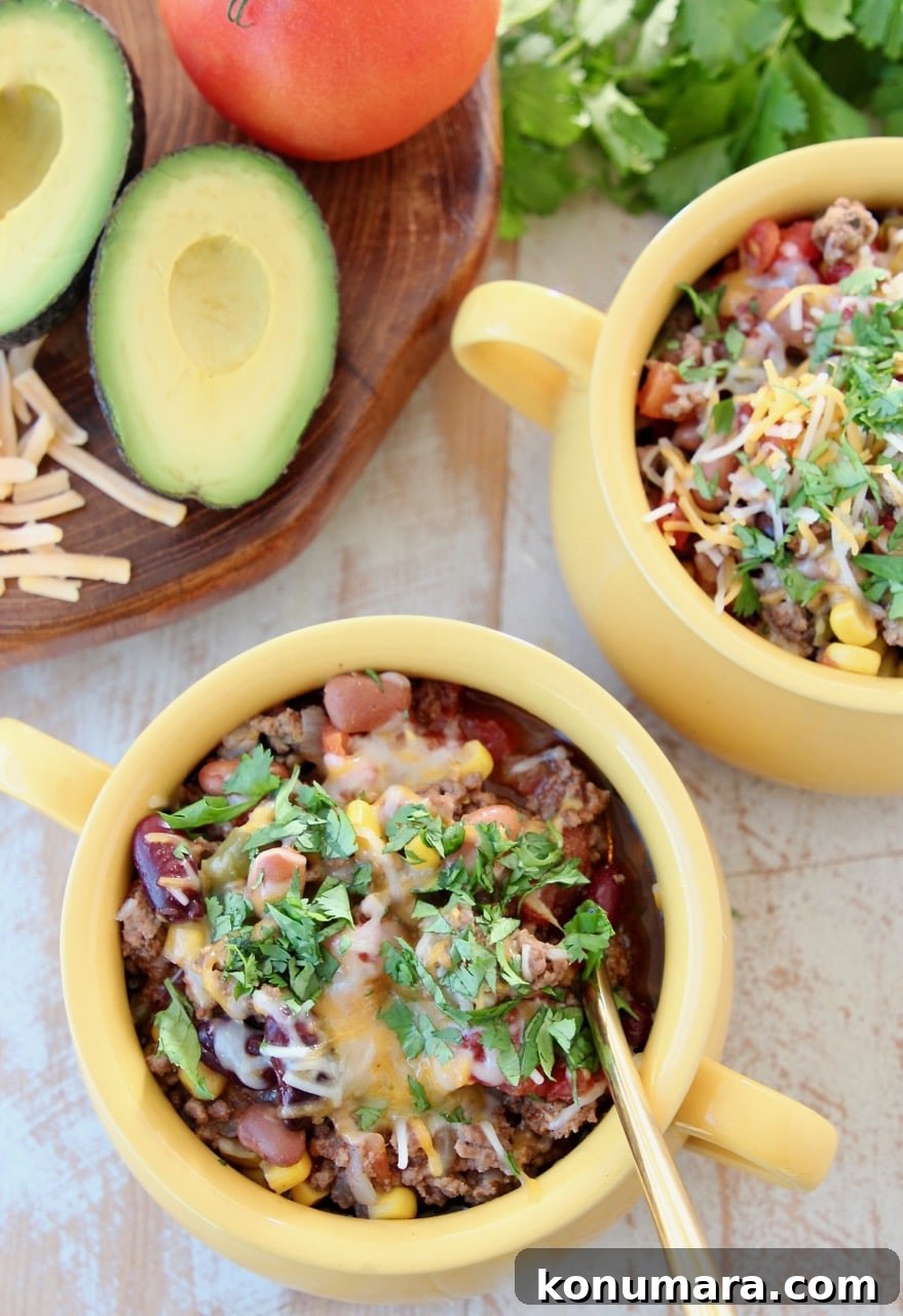 Slow Cooker Taco Soup with Ground Beef and Beans 5 Taco soup in yellow crocks with gold spoon, fresh cilantro, cheddar cheese and fresh avocado