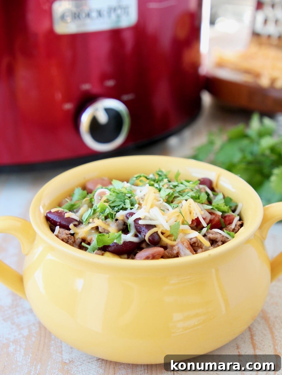 Slow Cooker Taco Soup with Ground Beef and Beans 6 Crockpot taco soup in yellow crock with cheddar cheese and fresh cilantro and red crock pot