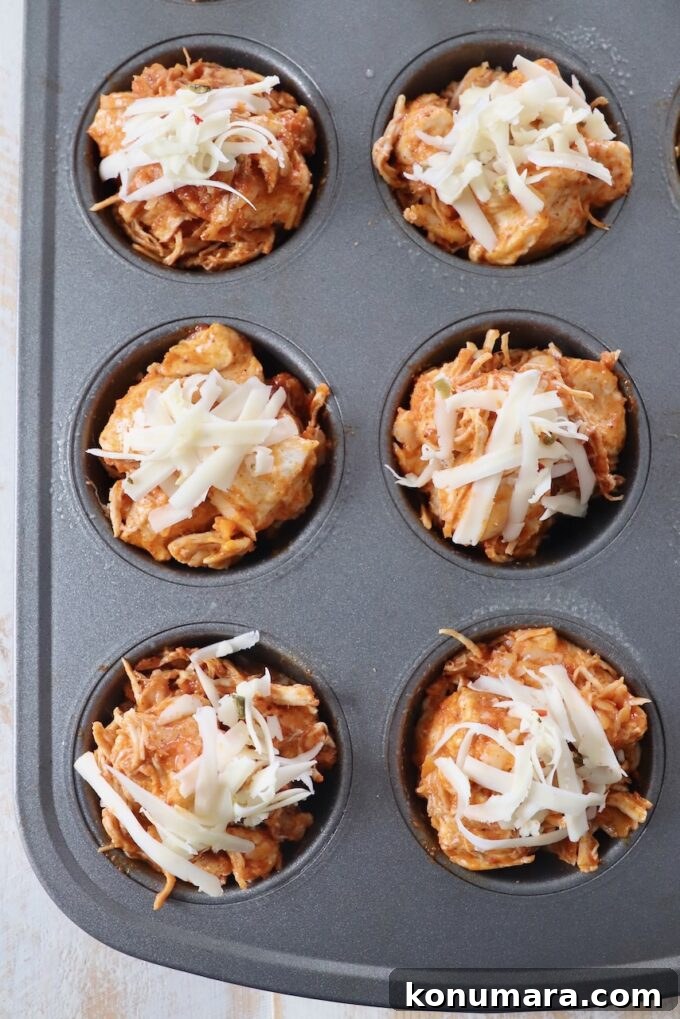 Pull-Apart Buffalo Chicken Rolls Recipe 7 buffalo chicken rolls in muffin tin topped with shredded cheese