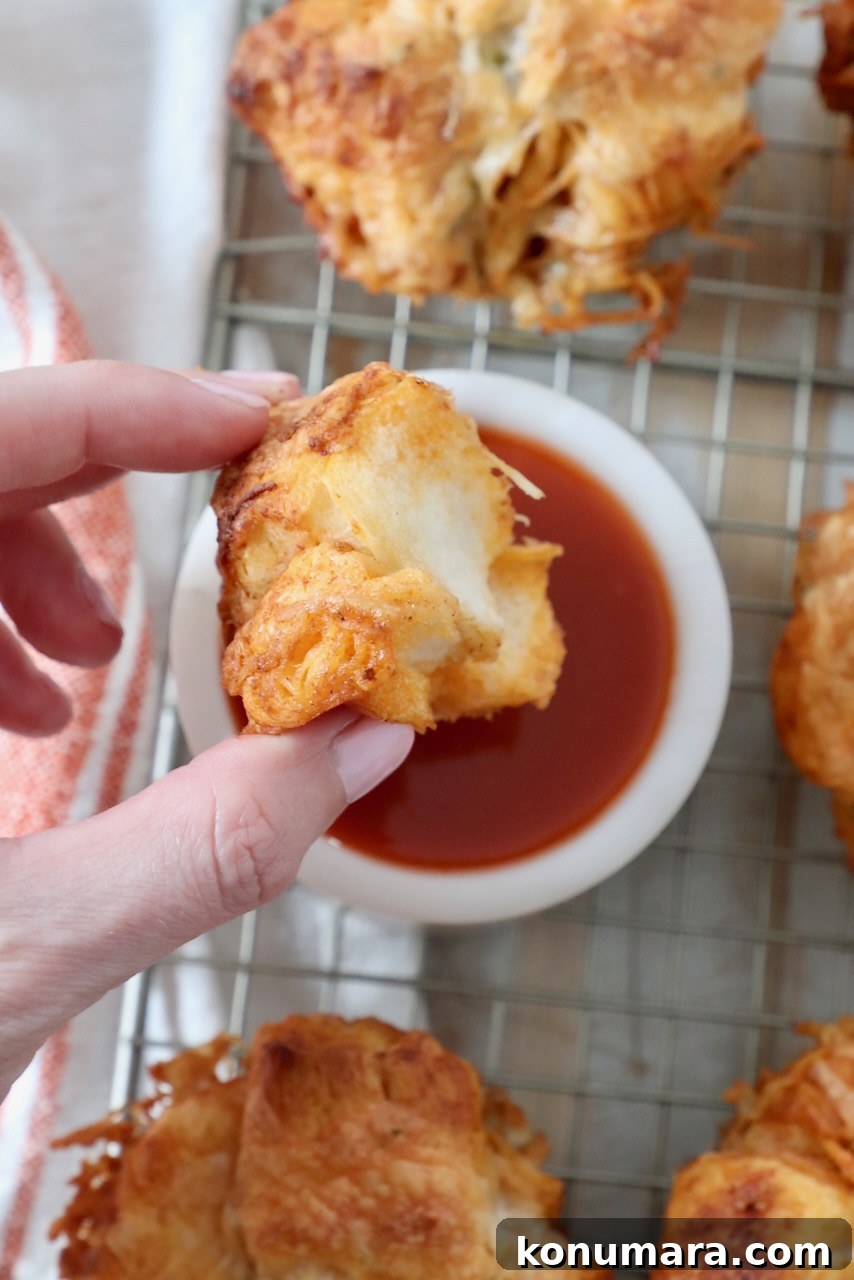 Pull-Apart Buffalo Chicken Rolls Recipe 9 hand dipping roll into bowl of buffalo sauce