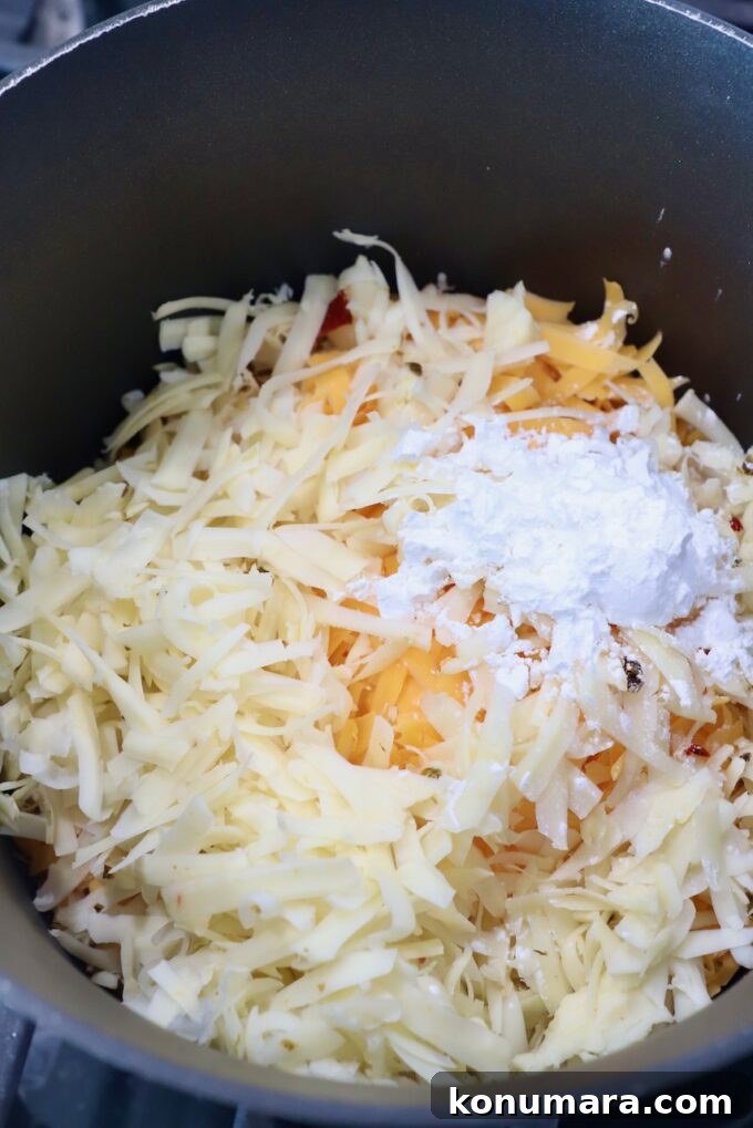 Homemade Nacho Cheese Sauce for Dips and Tacos 4 shredded cheese in sauce pot with cornstarch