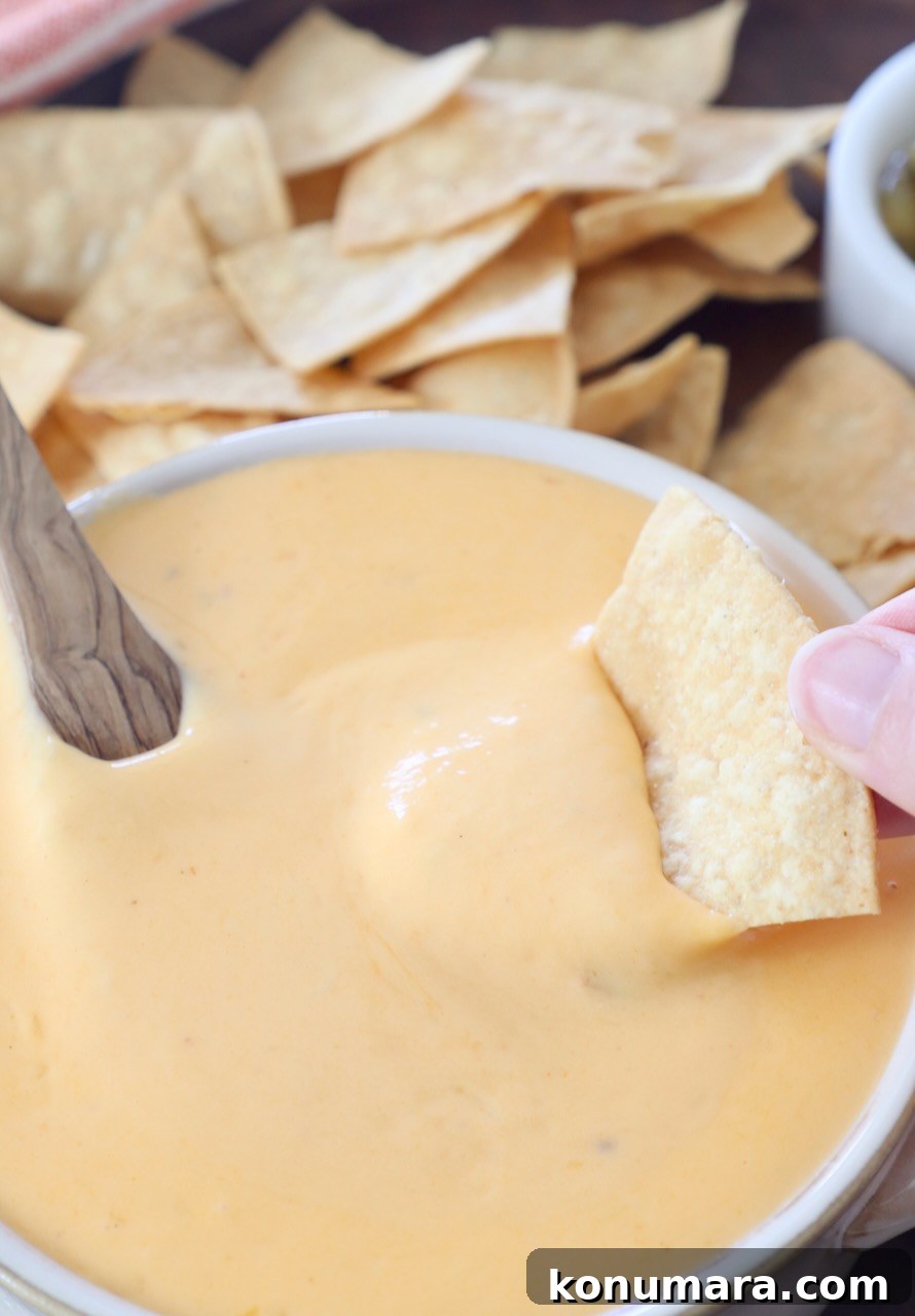 Homemade Nacho Cheese Sauce for Dips and Tacos 8 tortilla chip dipped into bowl of nacho cheese sauce