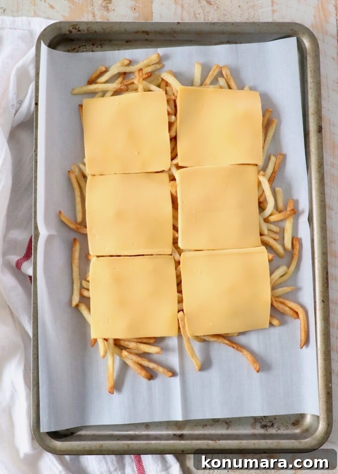 cooked fresh fries on baking sheet topped with slices of cheese