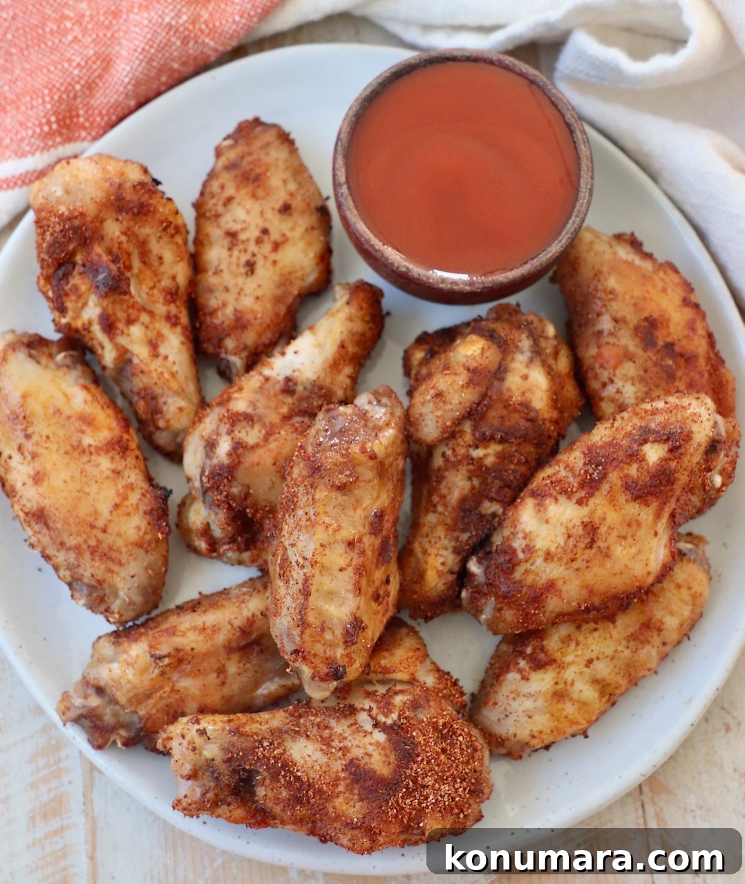 cooked chicken wings on plate with small bowl of buffalo sauce on the side