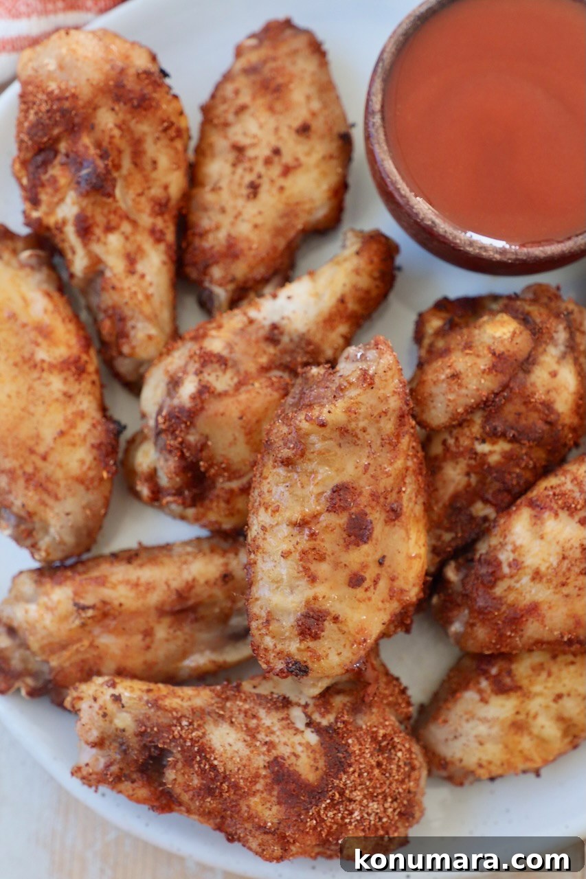 cooked chicken wings on plate with side of buffalo sauce in small bowl