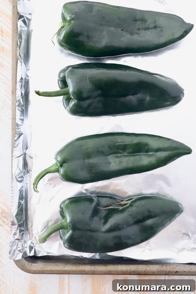 How to Roast Poblano Peppers for Salsa and Stuffing 3 raw poblano peppers on foil lined baking sheet