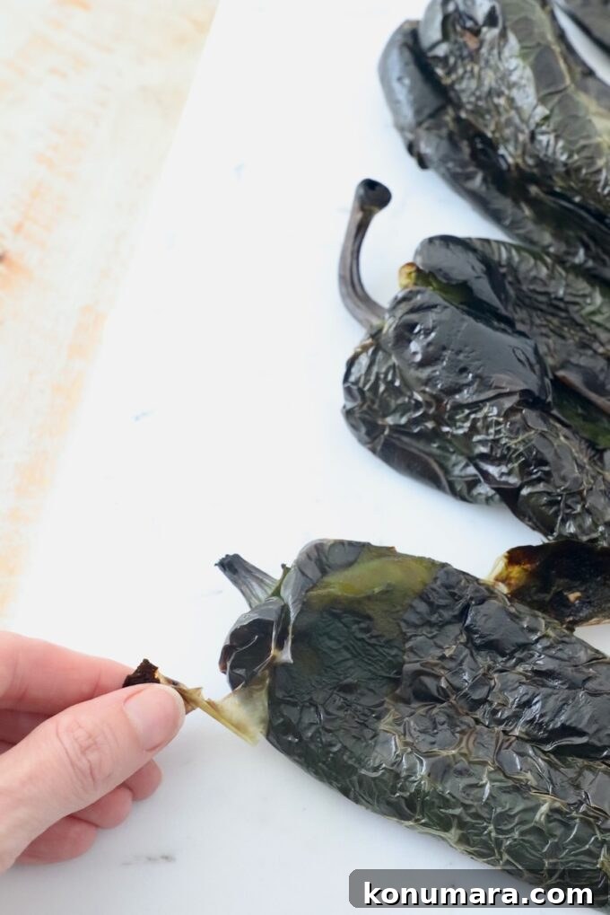 How to Roast Poblano Peppers for Salsa and Stuffing 6 hand peeling roasted poblano pepper on cutting board