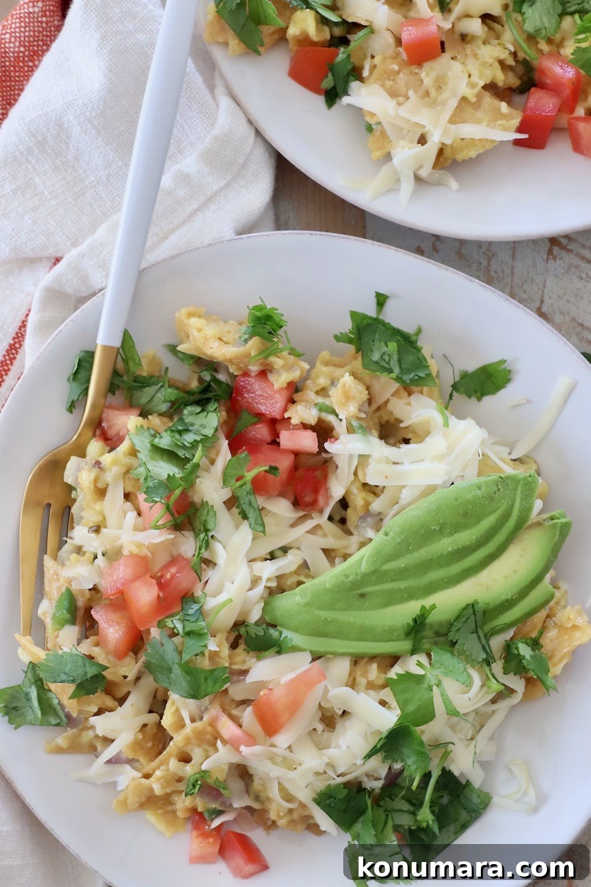 Classic Spanish Migas Recipe with Chorizo and Fried Eggs 2 migas on a white plate topped with sliced avocado
