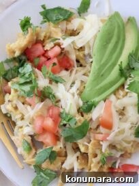 migas on plate with fork, topped with sliced avocado