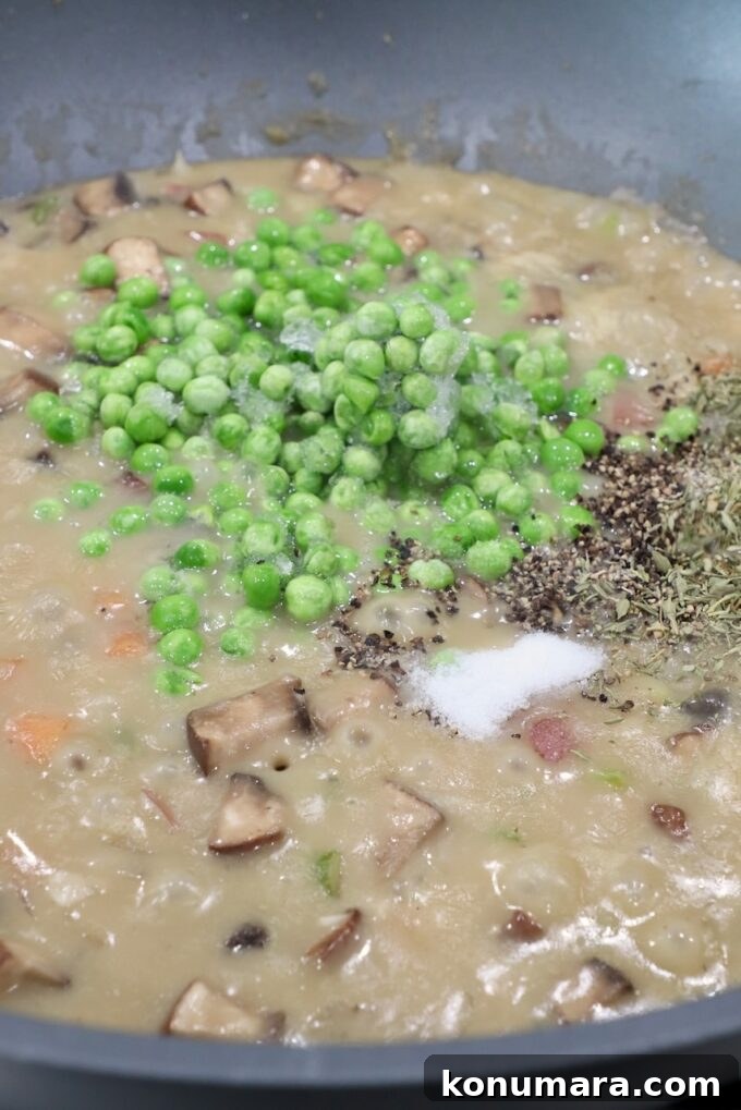frozen peas and spices in pan of vegetable pot pie filling