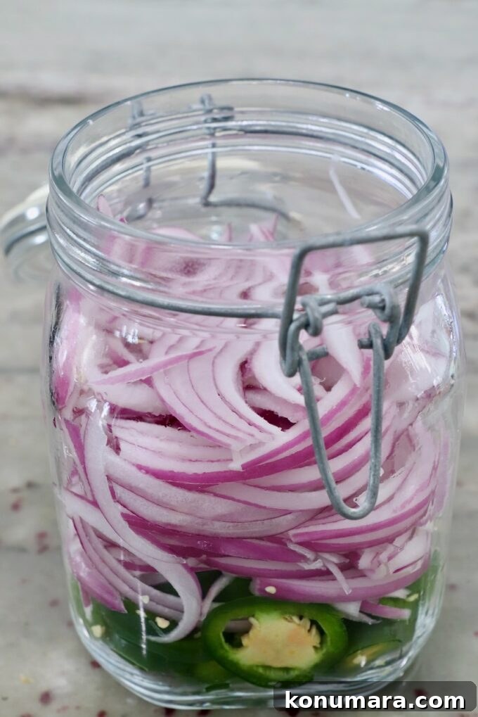 sliced red onions and jalapenos in large glass jar