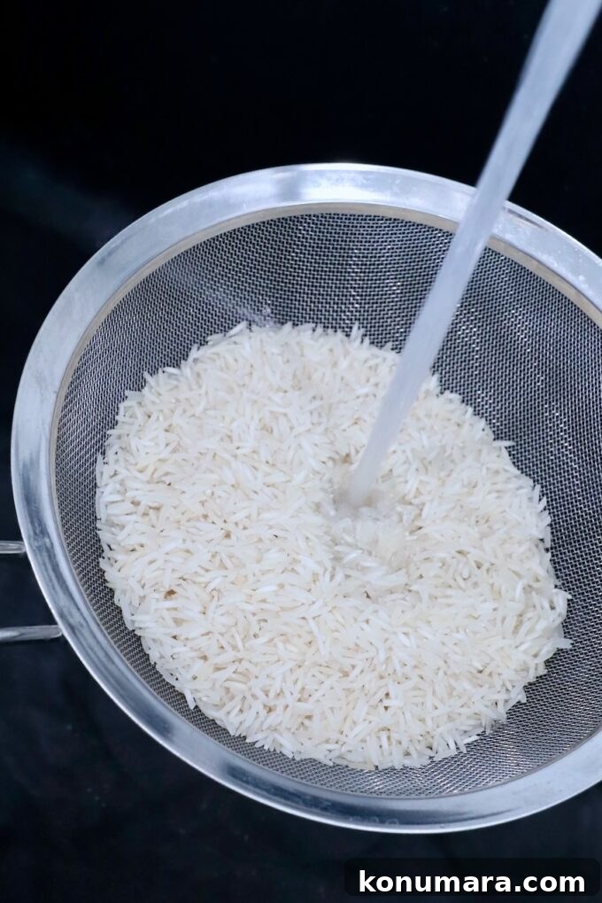 How to Make Fluffy Basmati Rice in the Instant Pot 3 white rice in mesh strainer in sink with water pouring over the rice