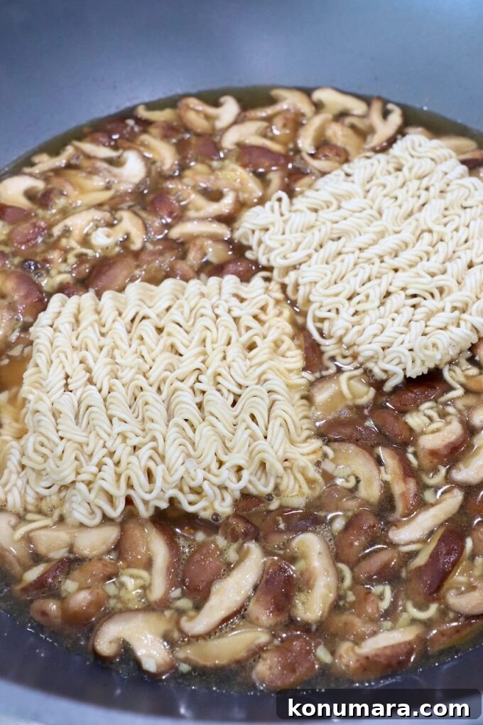Vegetarian Ramen Recipe: Miso Umami Broth with Vegetables 5 ramen noodles in large pot on stove with sliced mushrooms and broth