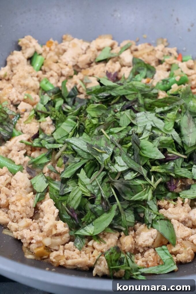 Spicy Thai Basil Chicken (Pad Krapow) Recipe 7 fresh Thai basil in large pan with cooked ground chicken