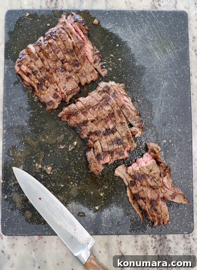 sliced grilled skirt steak on cutting board with large knife