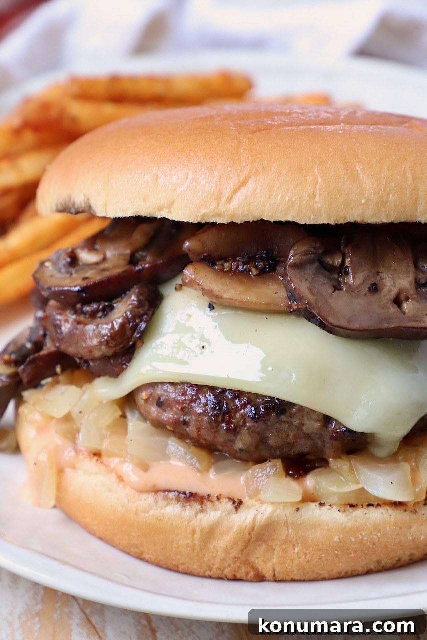 Cooked cheeseburger on plate topped with sauteed mushrooms