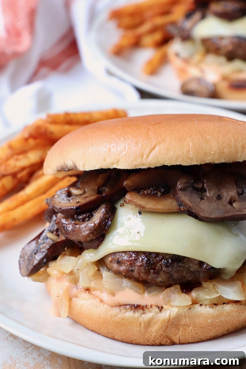 Mushroom swiss burger on plate with seasoned fries