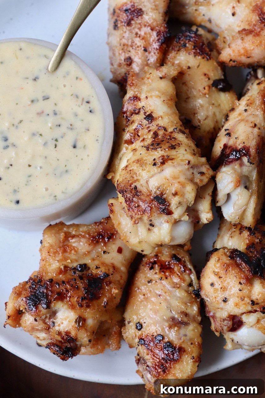 grilled chicken wings on plate with a small bowl of garlic parmesan sauce on the side