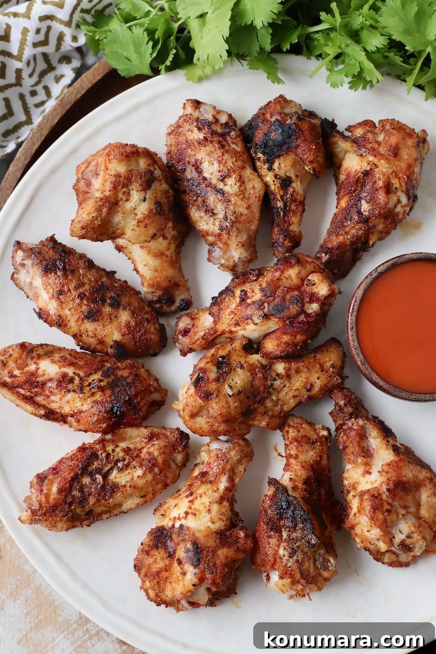 grilled chicken wings on plate with small bowl of buffalo sauce
