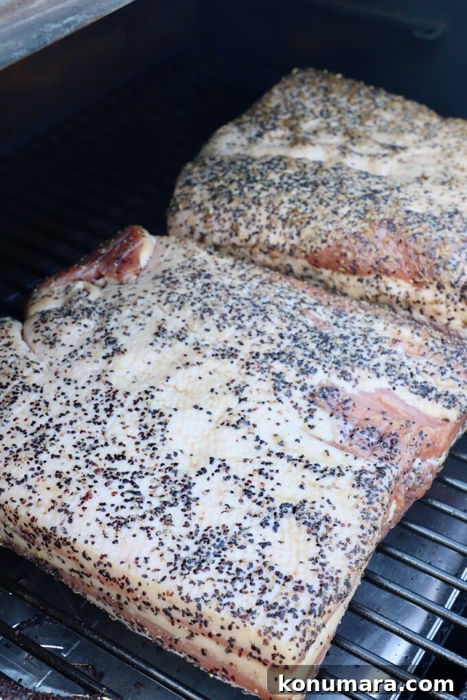two seasoned pork bellies on a smoker