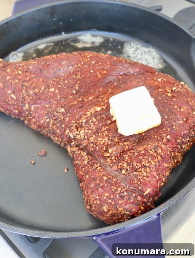 smoked seasoned tri tip in cast iron skillet topped with butter