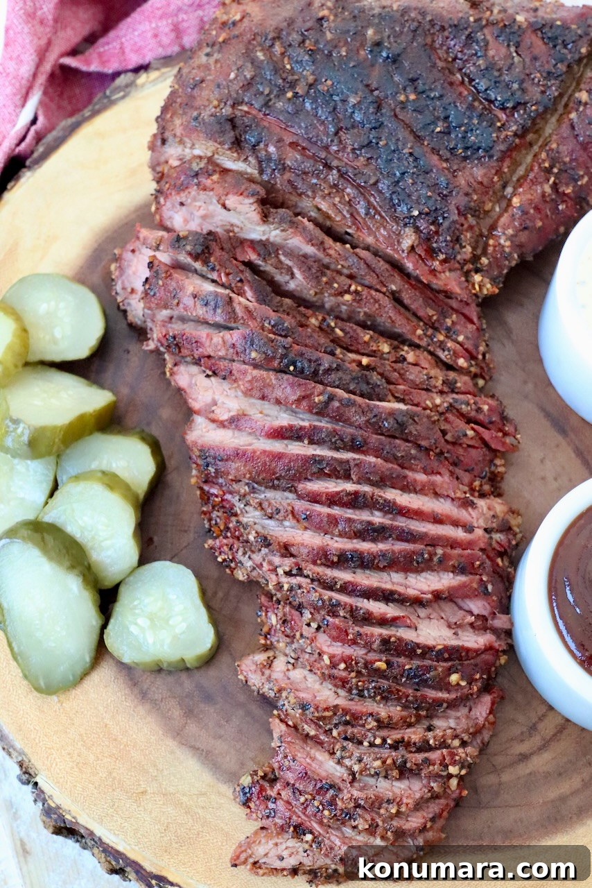 sliced smoked tri tip on cutting board with pickles