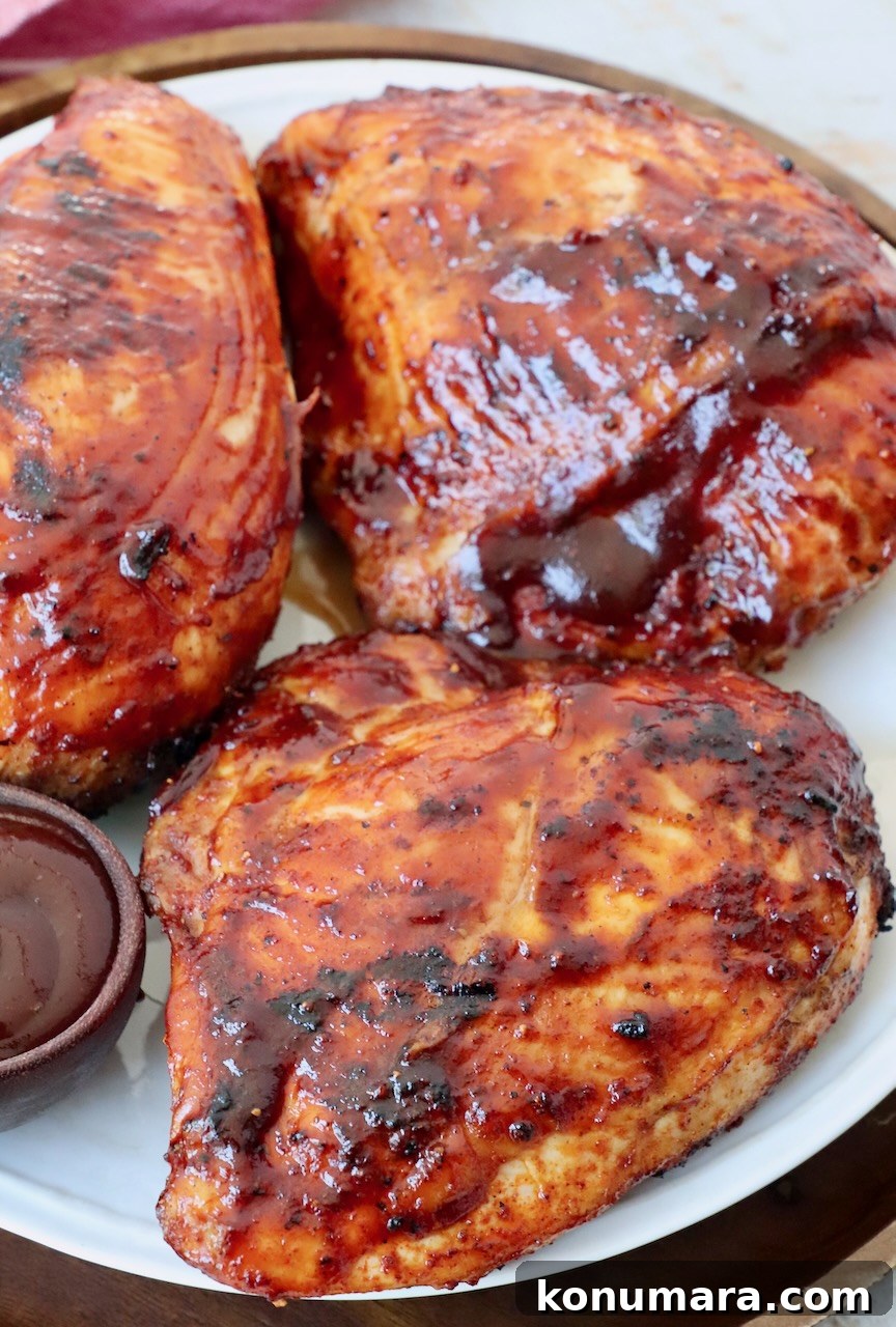 Juicy BBQ Chicken Recipe with Smoky Barbecue Sauce 2 pieces of grilled bone-in bbq chicken breasts on plate