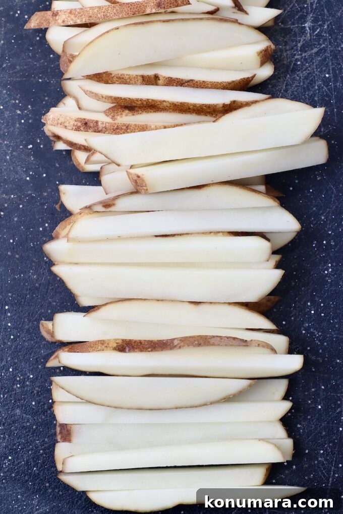 potatoes sliced into french fries on cutting board