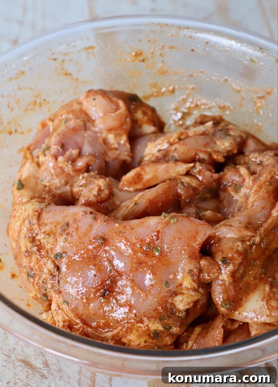 raw chicken thighs covered in marinade in large glass bowl