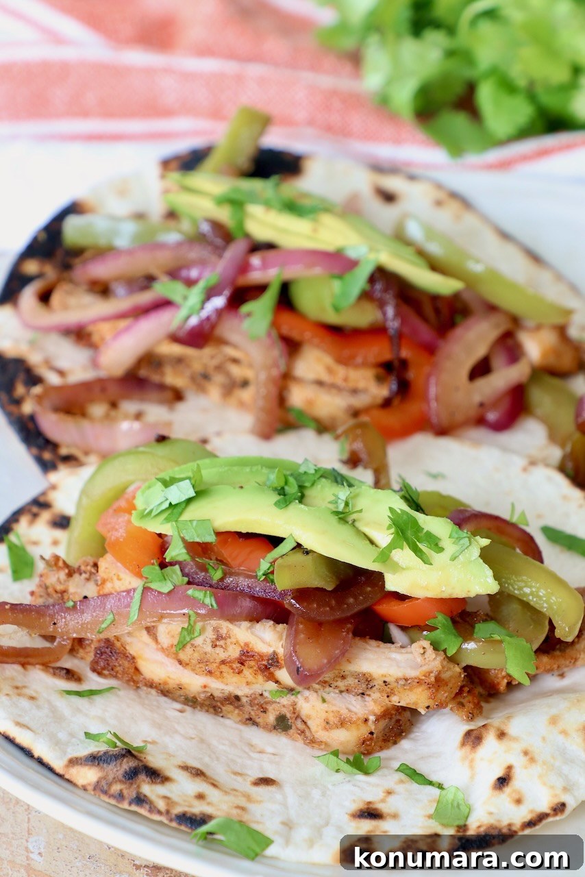 chicken fajitas on plate topped with sliced avocado and cilantro