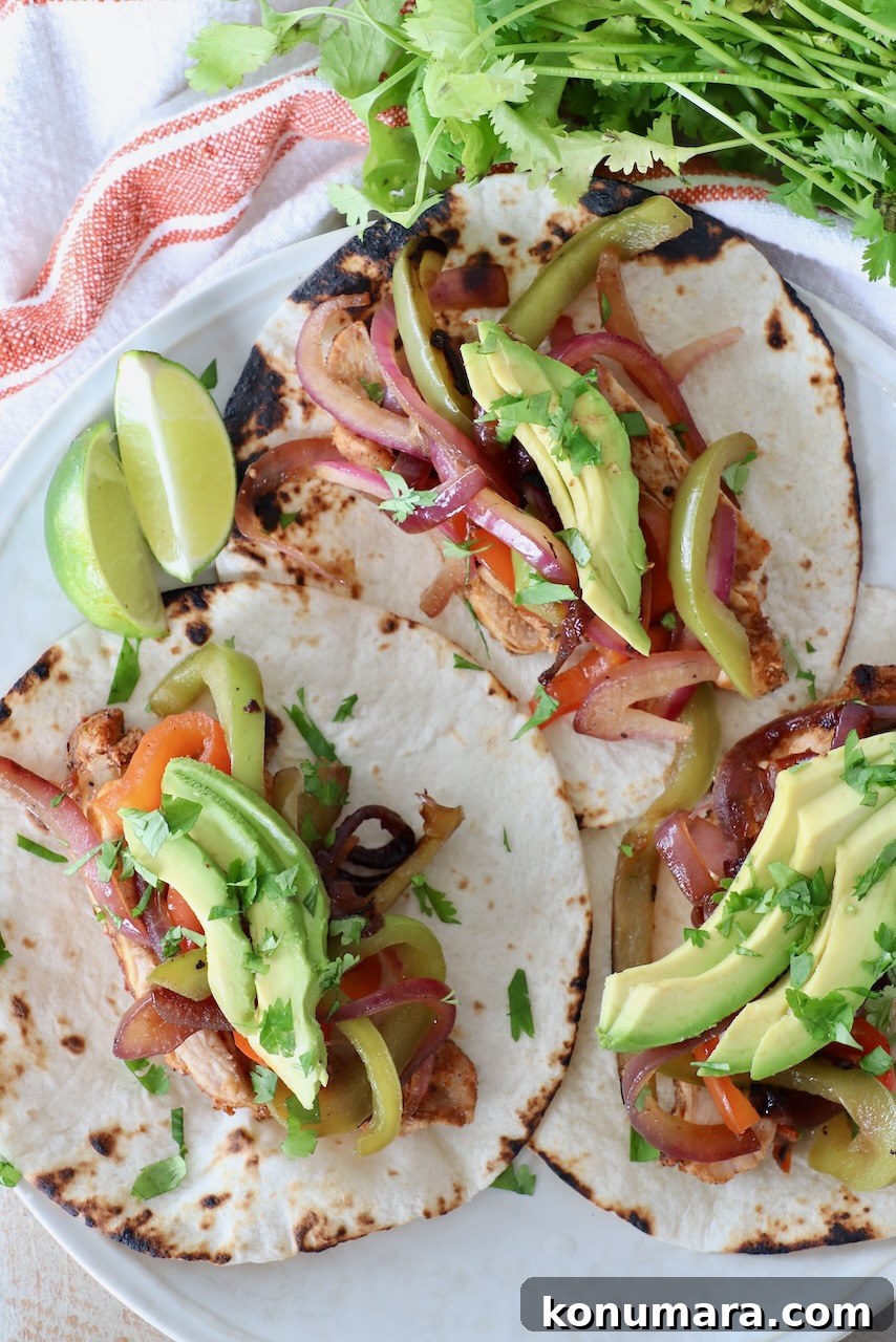 three chicken fajitas on plate topped with slices of avocado