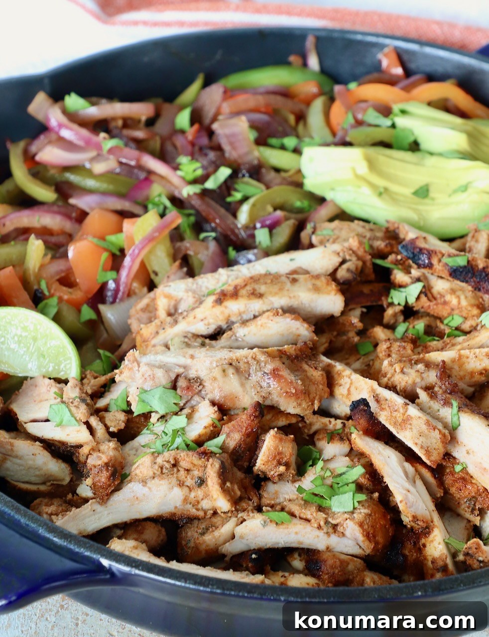 sliced grilled chicken in skillet with cooked sliced bell peppers and onions