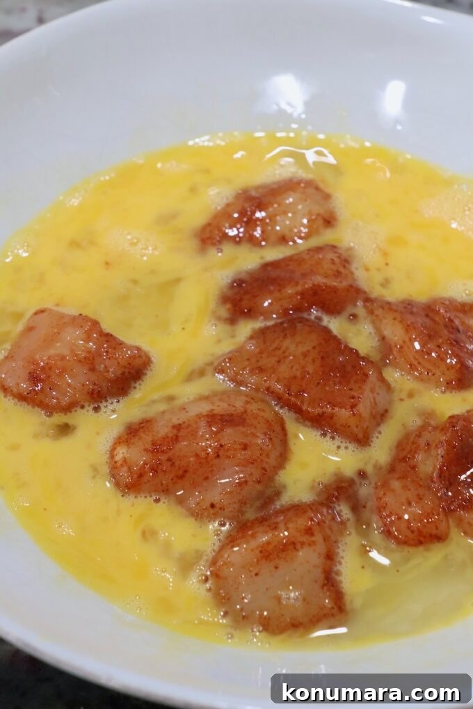seasoned pieces of chicken breast in bowl of whisked eggs
