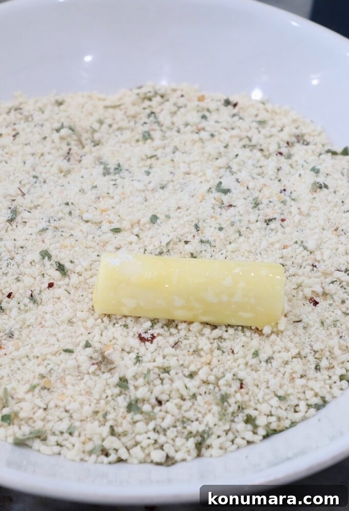piece of mozzarella on top of seasoned breadcrumbs in bowl