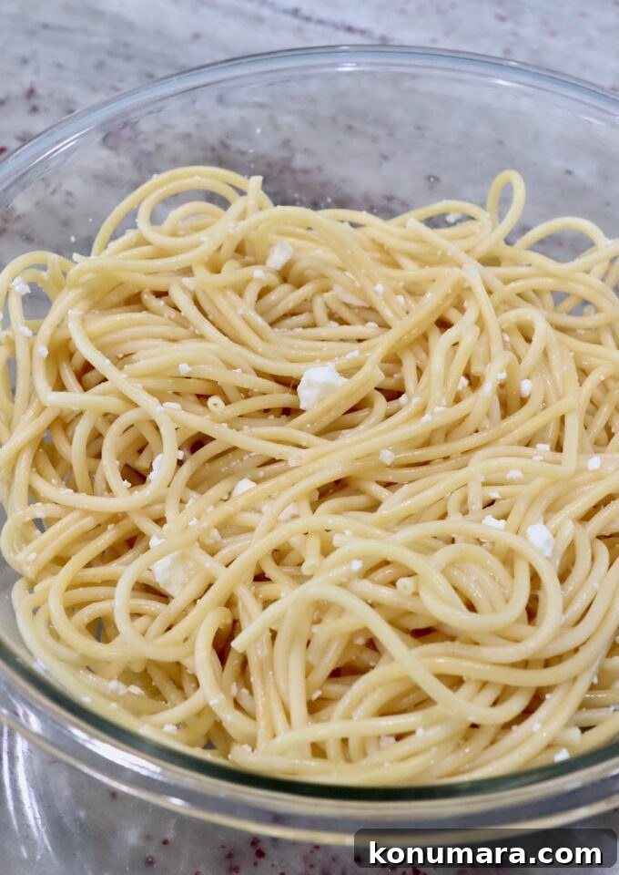 cooked pasta noodles in bowl with feta cheese crumbles