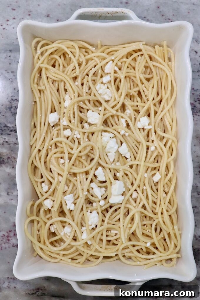 cooked pasta noodles in casserole dish with feta cheese crumbles