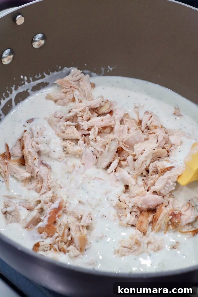 Creamy Garlic Parmesan Chicken Pasta Recipe 5 cooked, shredded chicken in pan with white sauce