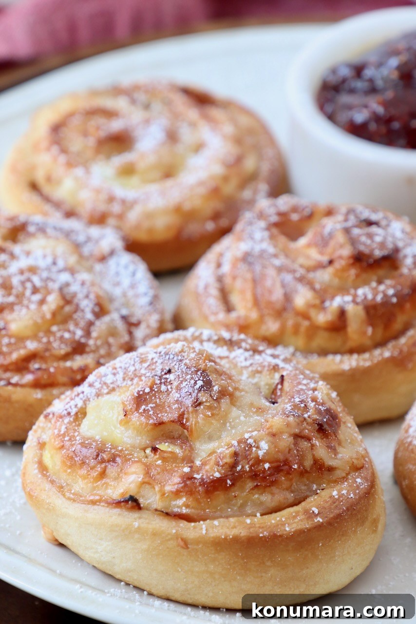 Cooked Monte Cristo rolls on a plate with a small bowl of raspberry jam
