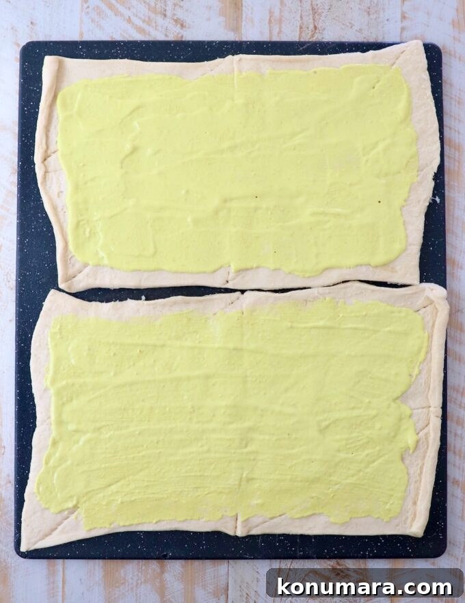 Mayonnaise and mustard combined and spread on sheets of crescent roll dough