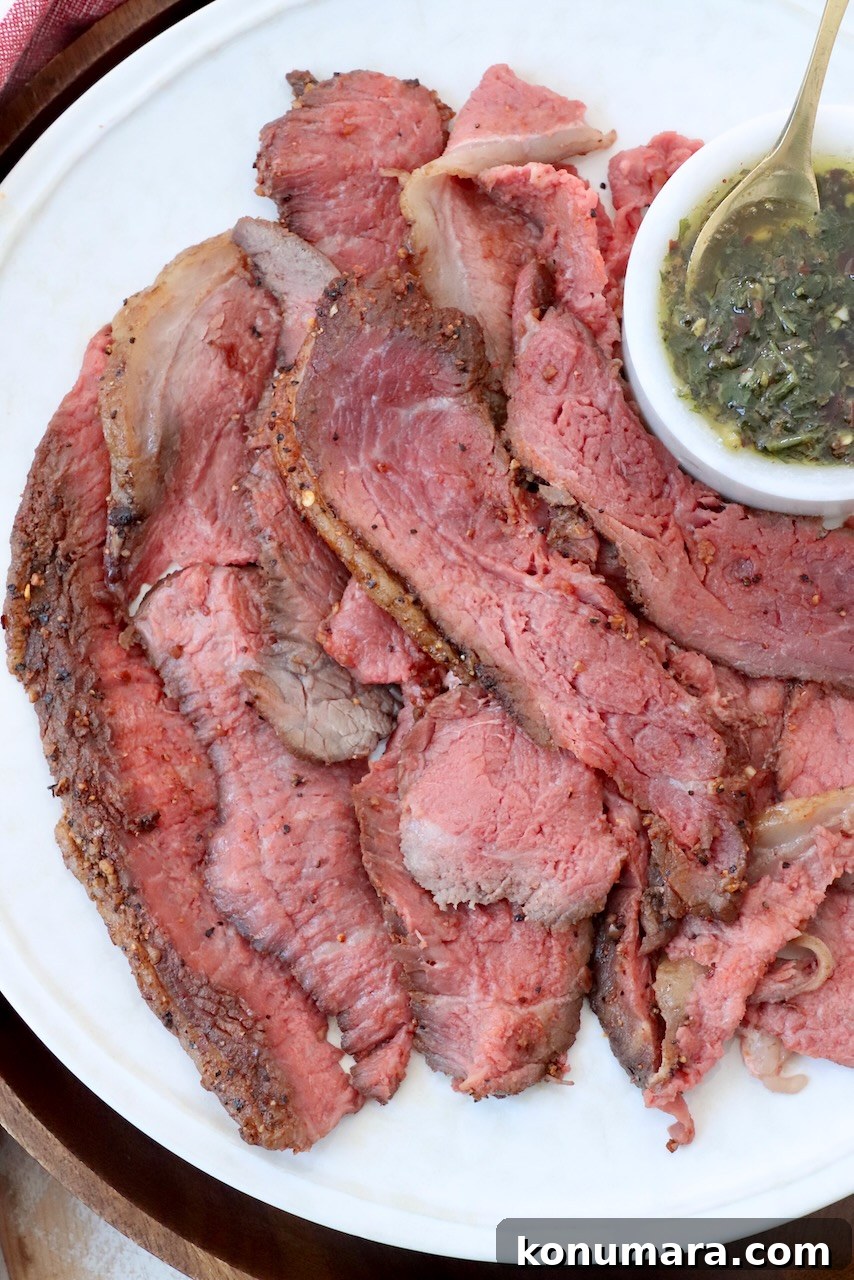 Rotisserie Picanha Recipe: Juicy Brazilian Rump Cap on the Spit 2 thinly sliced beef on large plate with a small bowl of herb butter sauce