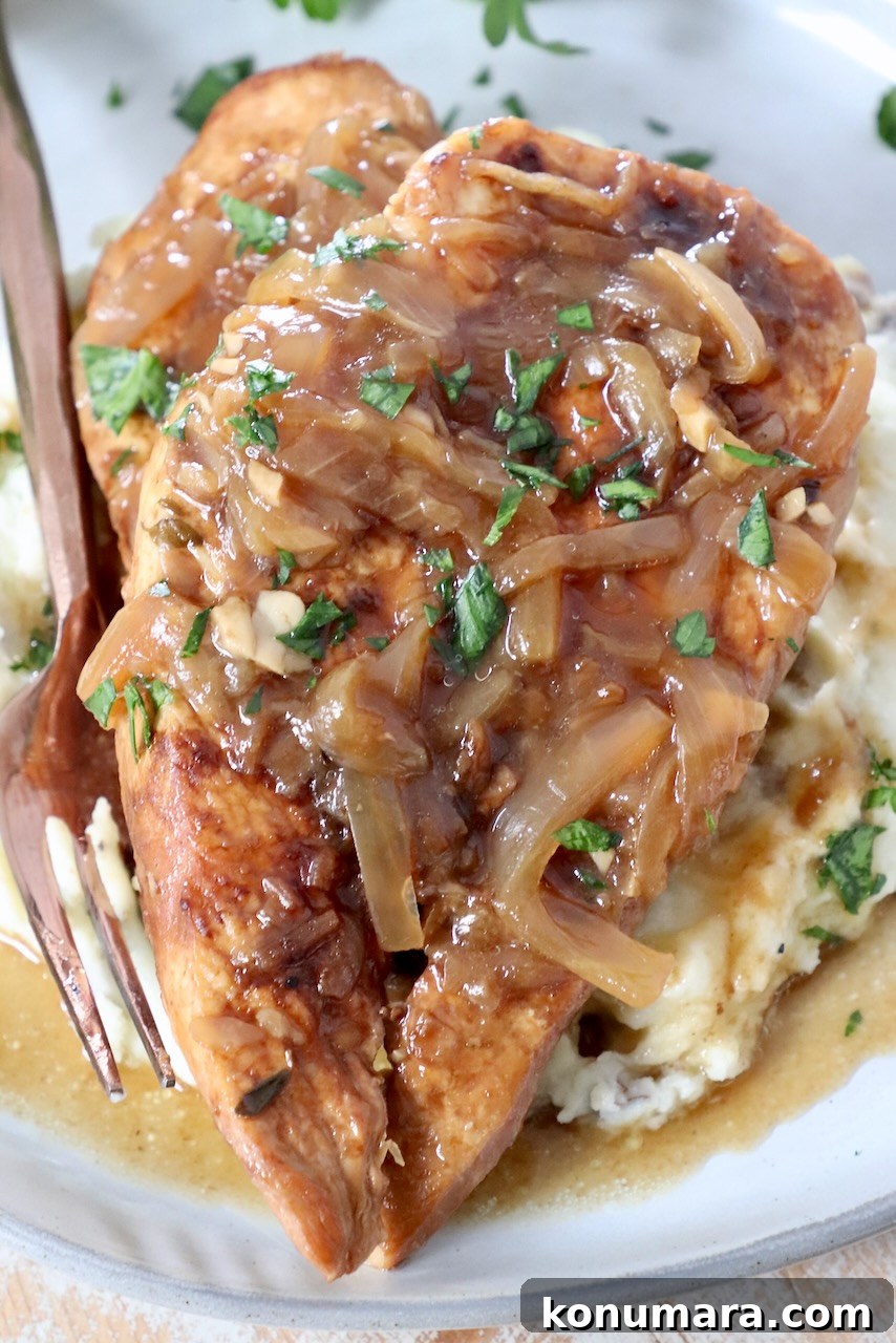 cooked chicken breasts on plate with caramelized onion gravy