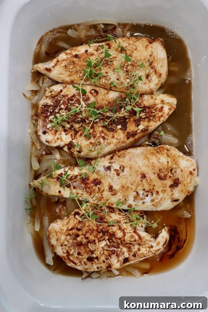 seared chicken breasts in slow cooker with fresh thyme sprigs and caramelized onions