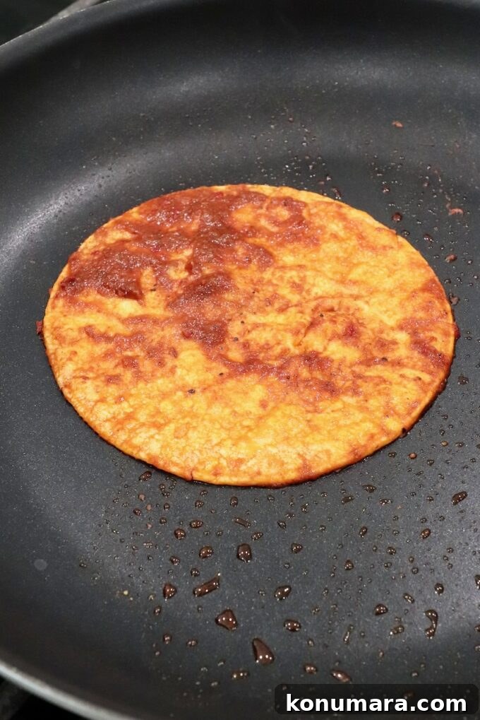 Quesabirria Recipe: Crispy Cheesy Birria Tacos 4 tortilla covered in sauce in skillet